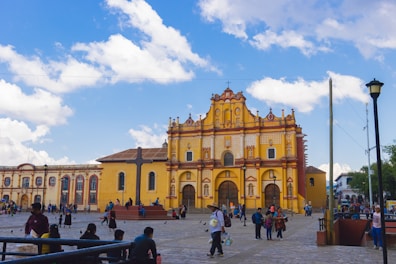 a group of people standing in front of a yellow building