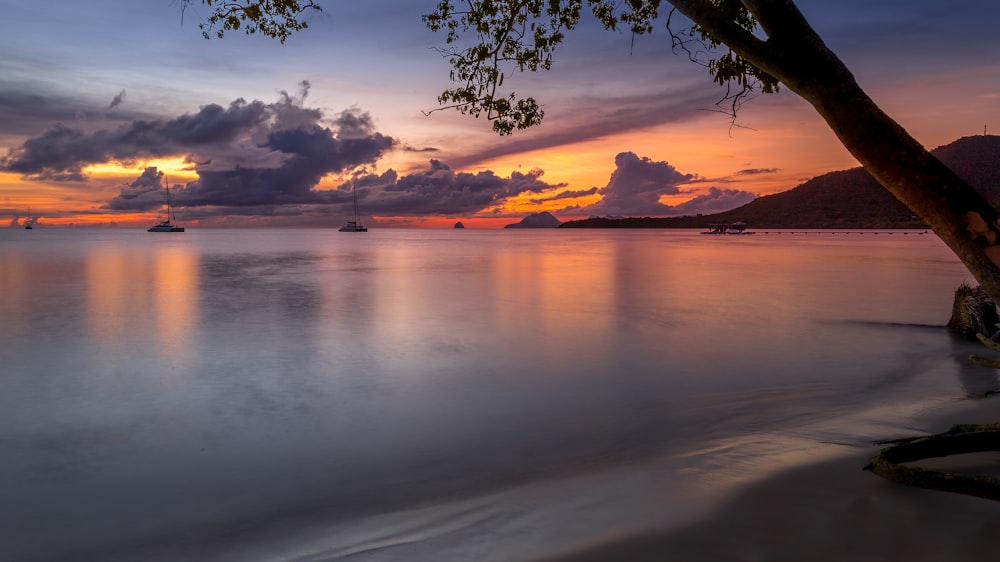 a beautiful sunset over the ocean with boats in the water