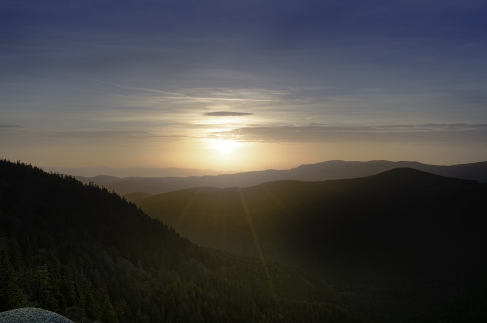 the sun is setting over a mountain range