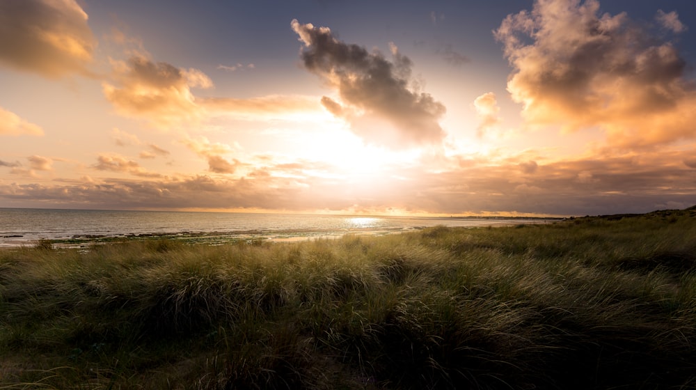 the sun is setting over the ocean on the beach