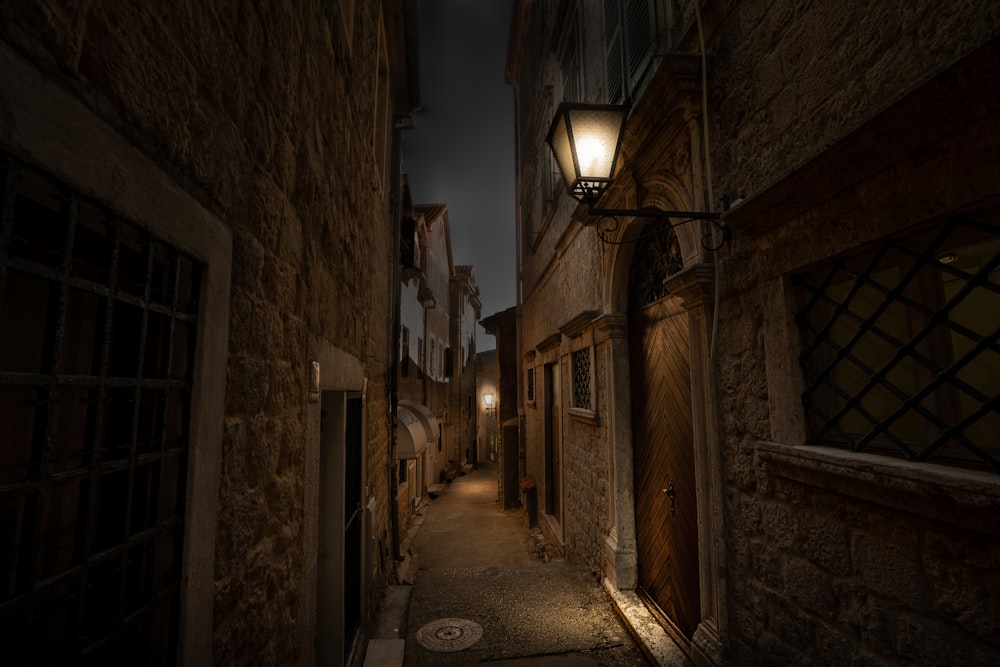 a dark alley with a lamp on the side of it