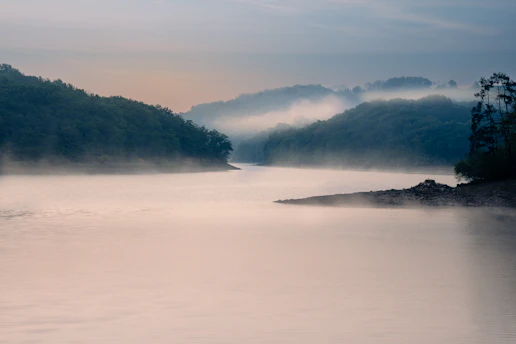 A serene river winding through misty hills at dawn, capturing the quiet beauty of an untouched landscape.