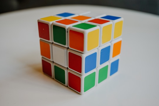 A Rubik's Cube with various colored squares, including red, blue, yellow, orange, green, and white, situated on a plain white surface.