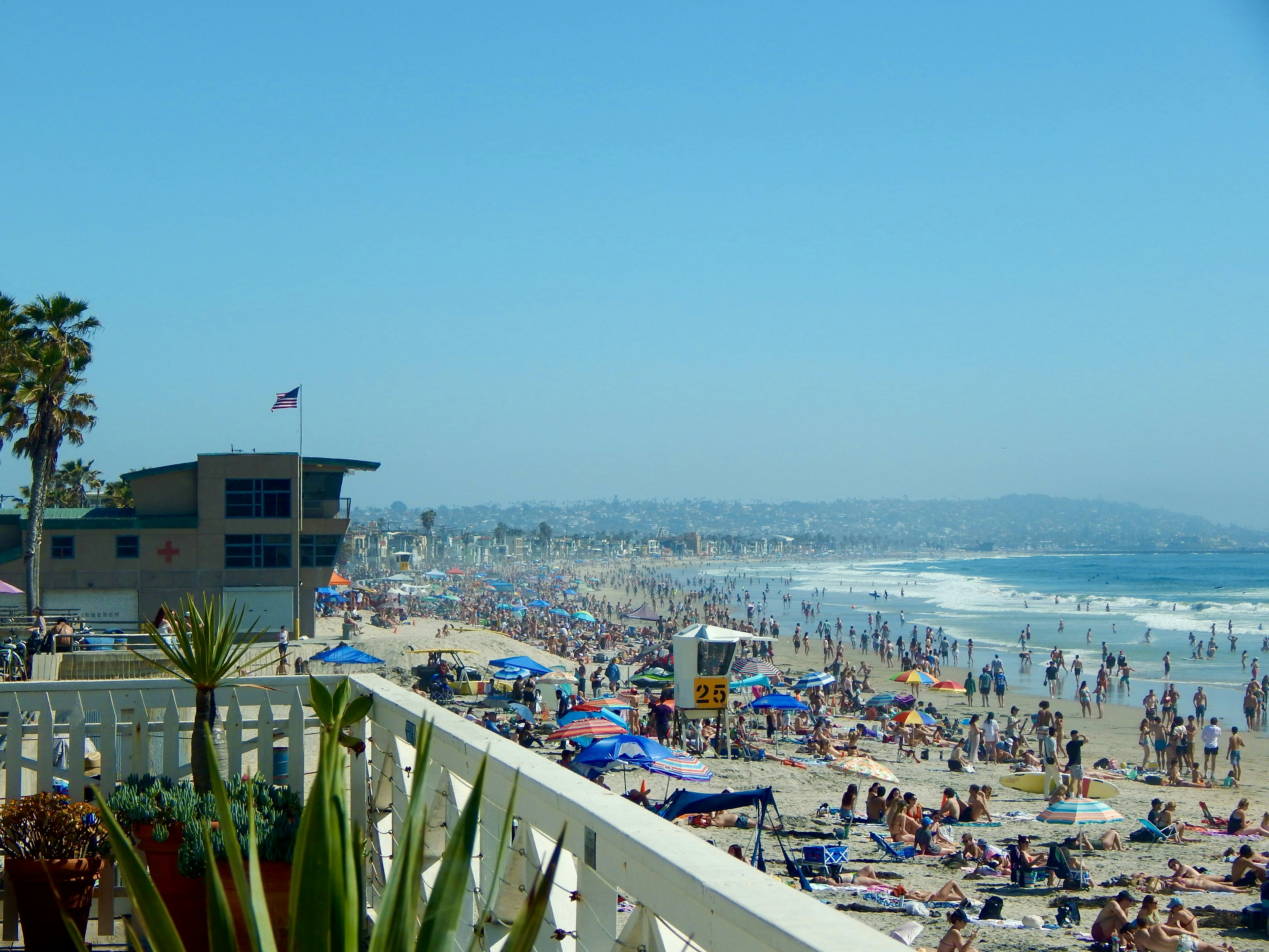 a crowded beach with a lot of people on it, A sunny day at Pacific Beach packed with people enjoying a beautiful day in San Diego.