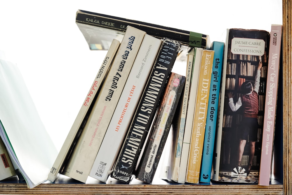 a bookshelf filled with lots of books on top of a wooden shelf
