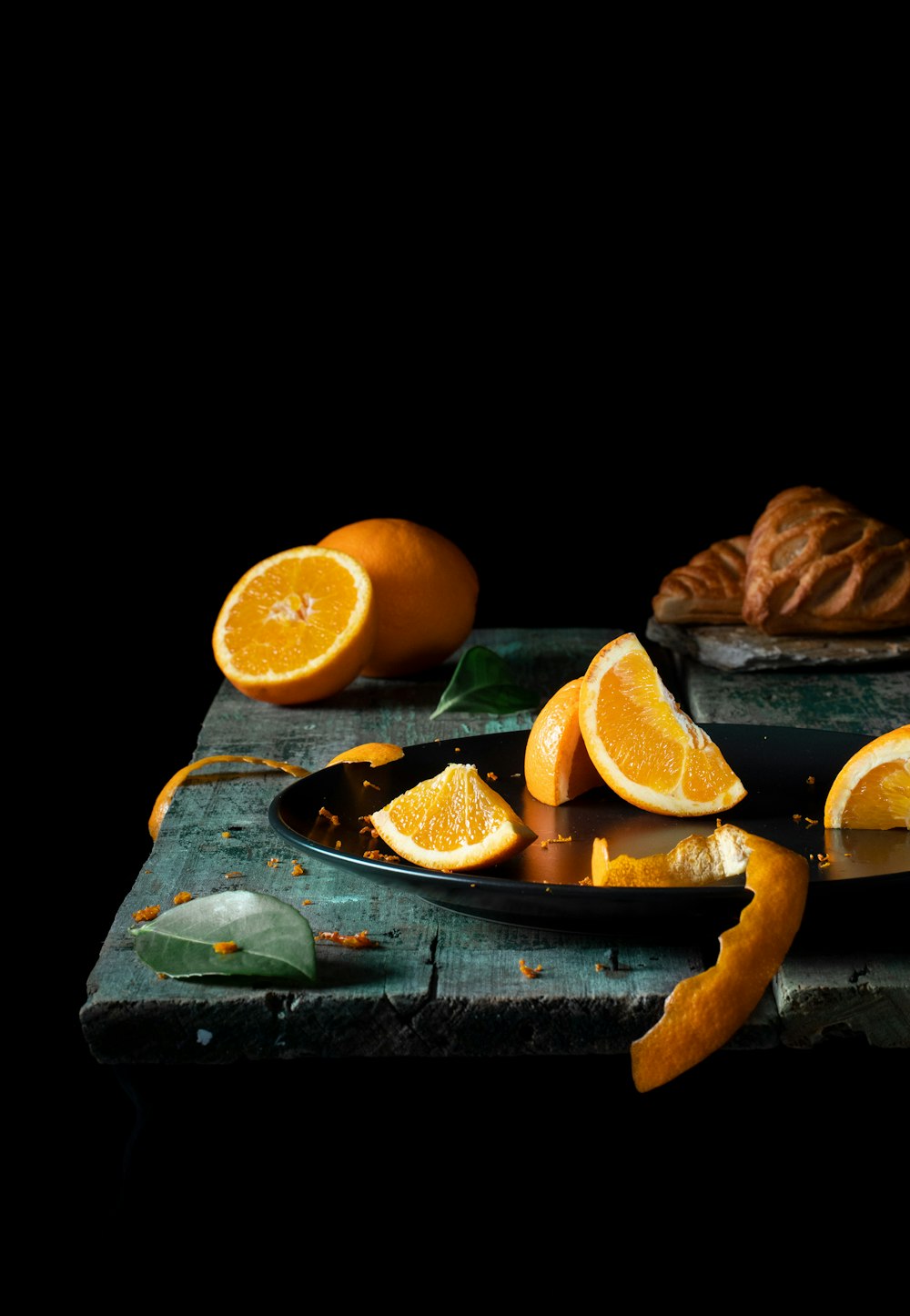 a table topped with sliced oranges and a croissant