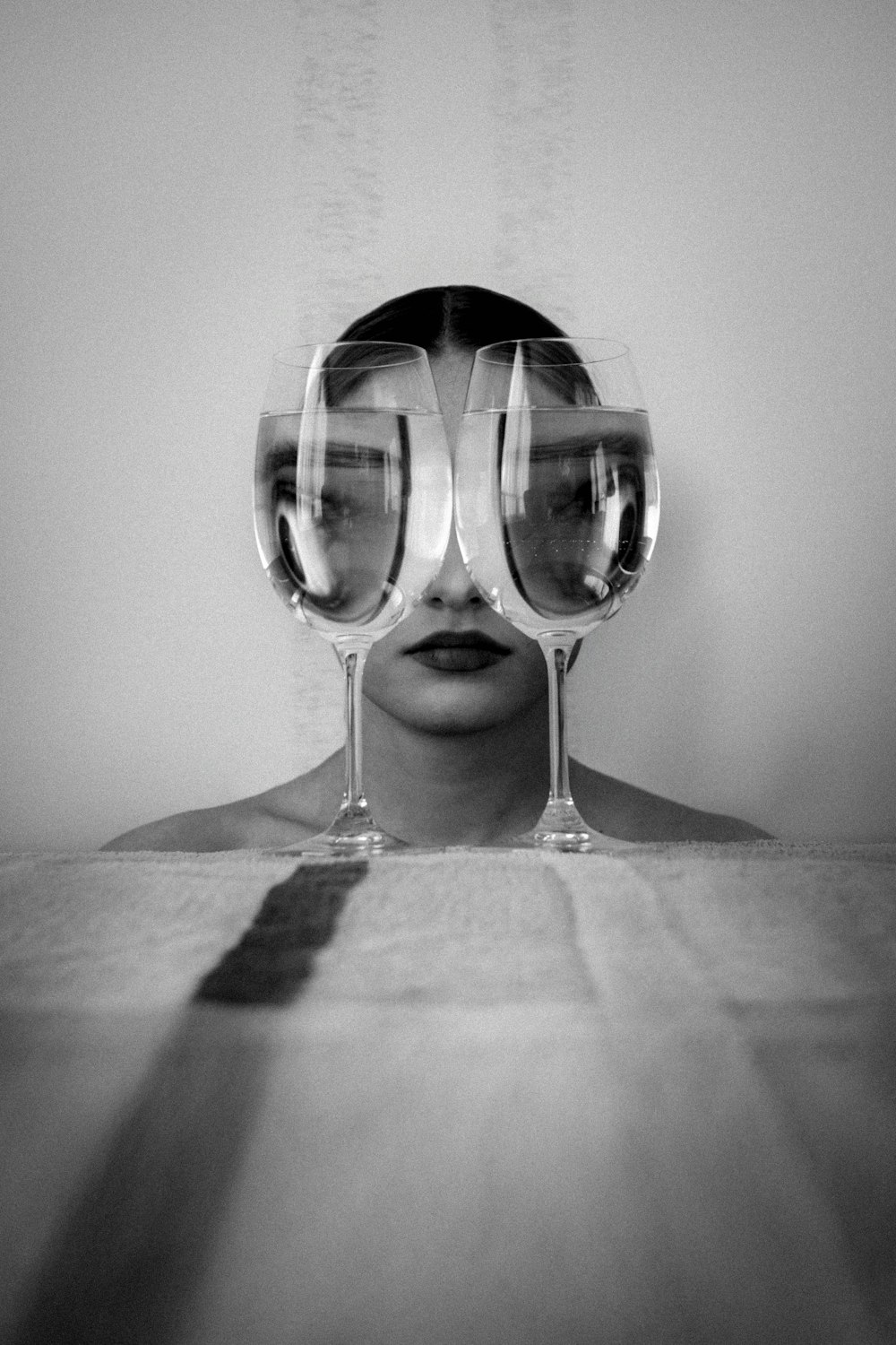 uma mulher com três taças de vinho na frente de seu rosto