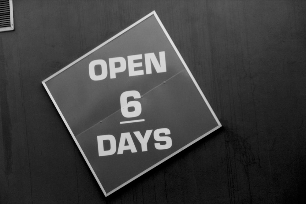 a black and white photo of a sign that says open 6 days