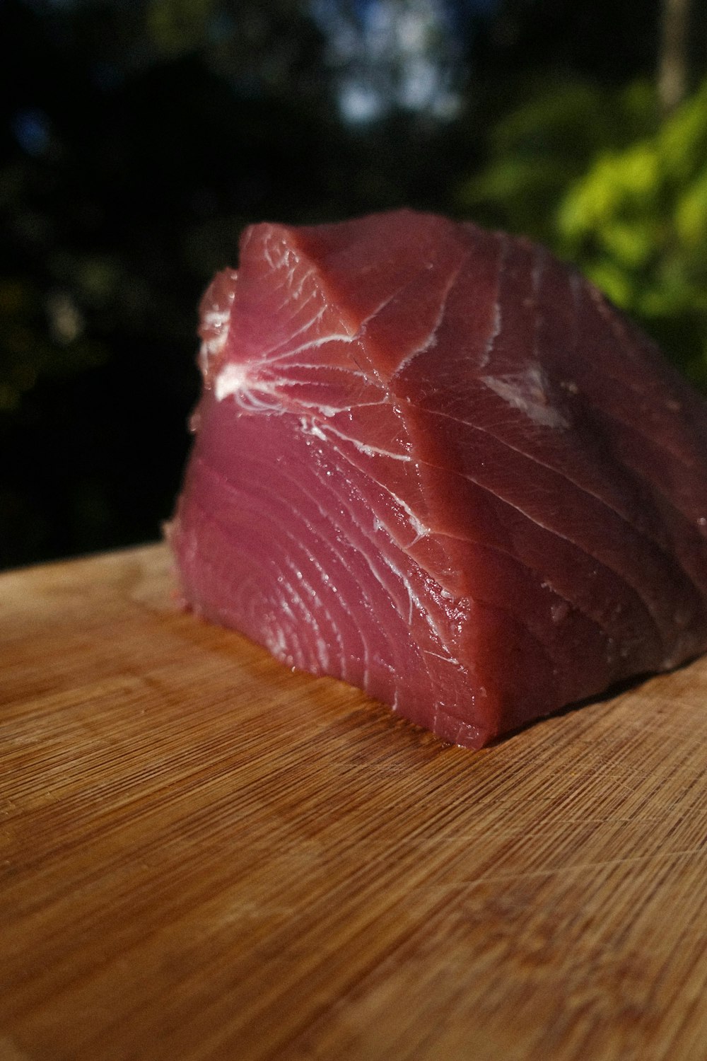 a piece of raw tuna sitting on top of a wooden cutting board