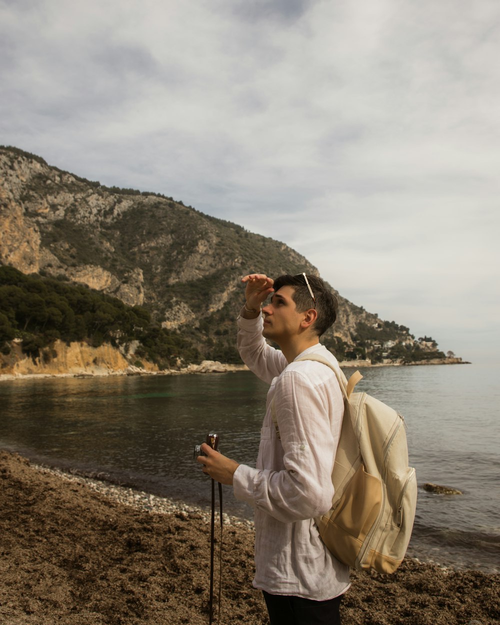 um homem em pé em uma praia olhando para a distância