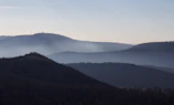 A serene landscape of mist rolling over distant hills at dawn.