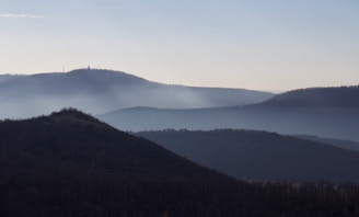 A serene landscape with soft morning light and mist over hills.