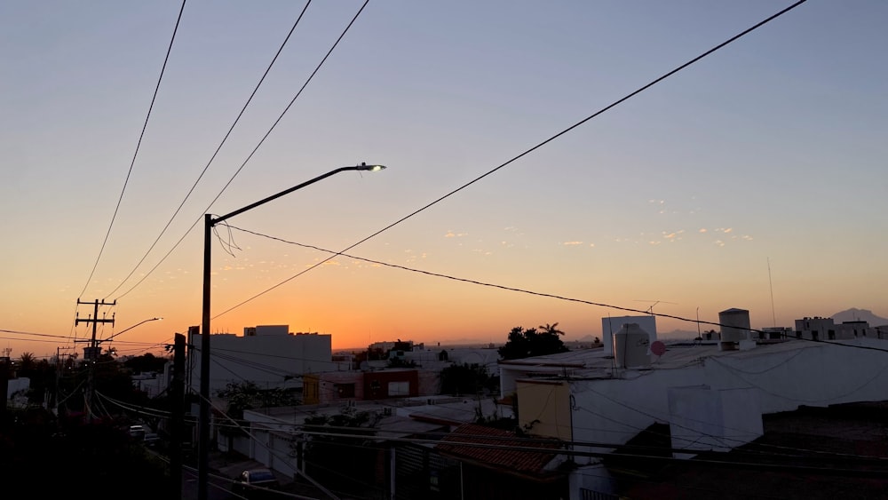 the sun is setting over a city with power lines