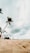 a man standing on top of a sandy beach next to a palm tree