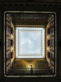 a person sitting on a bench in a room with a skylight