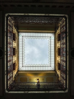 a person sitting on a bench in a room with a skylight