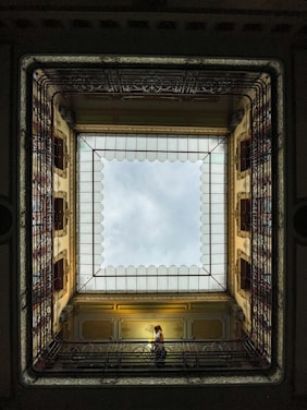 a person sitting on a bench in a room with a skylight