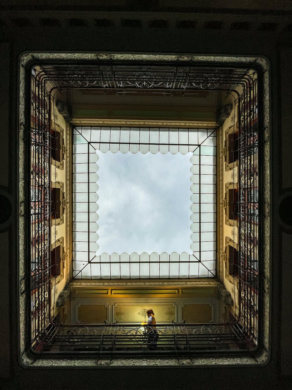 a person sitting on a bench in a room with a skylight