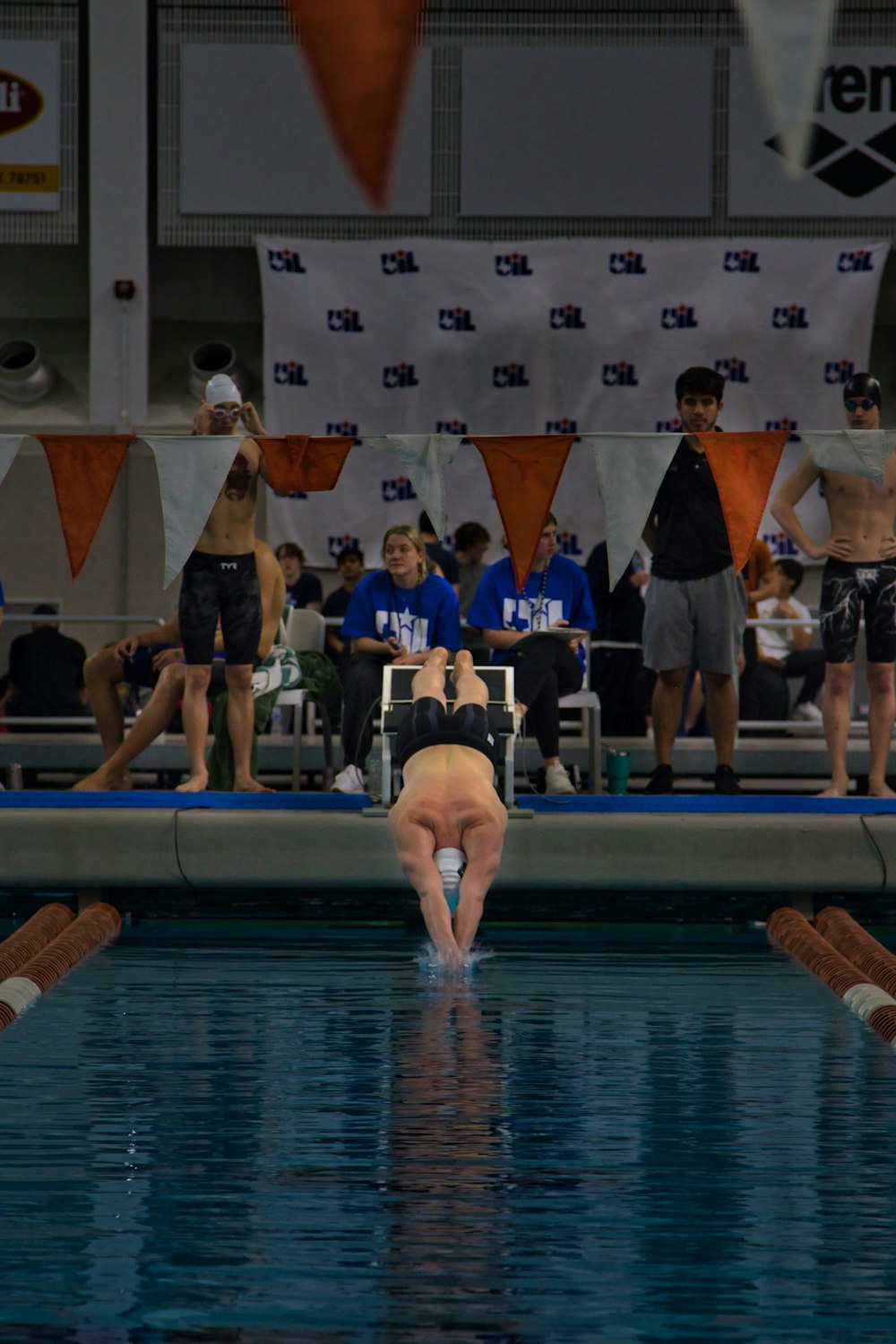 a man diving into a swimming pool while people watch