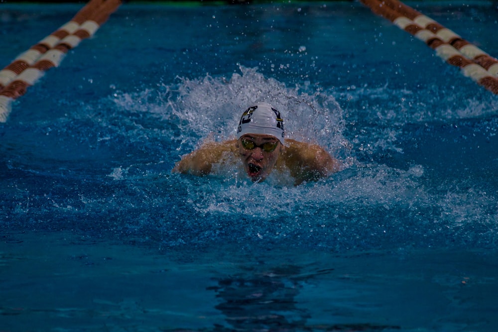 a man swimming in a pool with a hat on