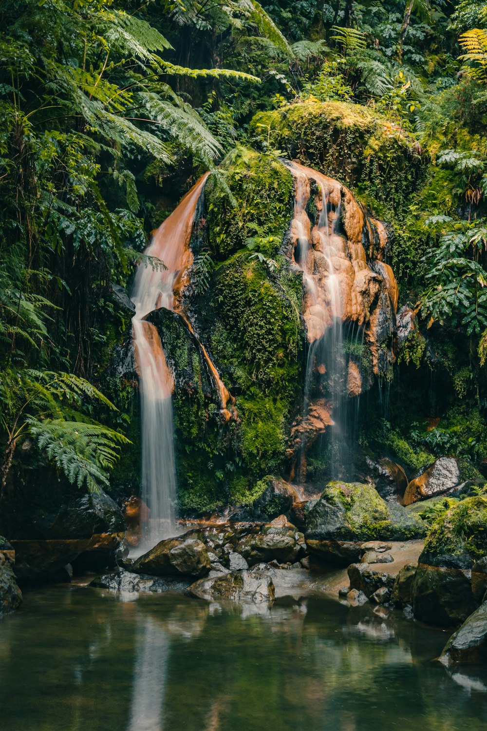 a waterfall in the middle of a lush green forest