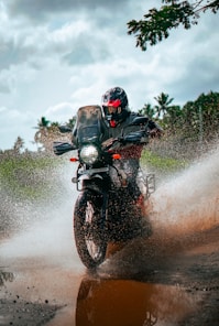 a man riding a motorcycle through a puddle of water