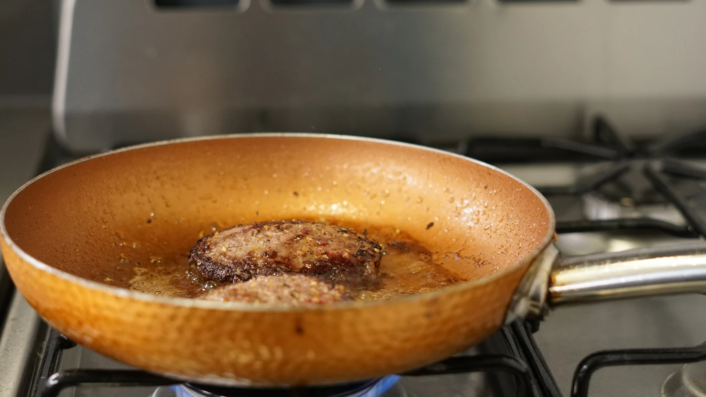 Sartén metálica sobre placa de cocina para explicar los recubrimientos de titanio