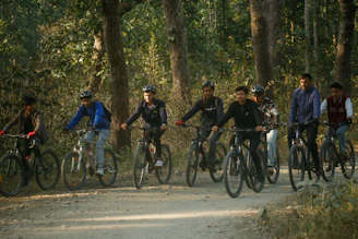 A group of friends laughing and biking together through a leafy park trail.