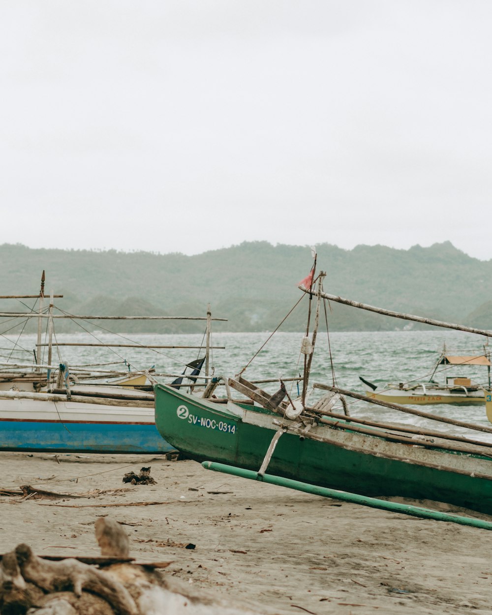 a couple of boats sitting on top of a sandy beach