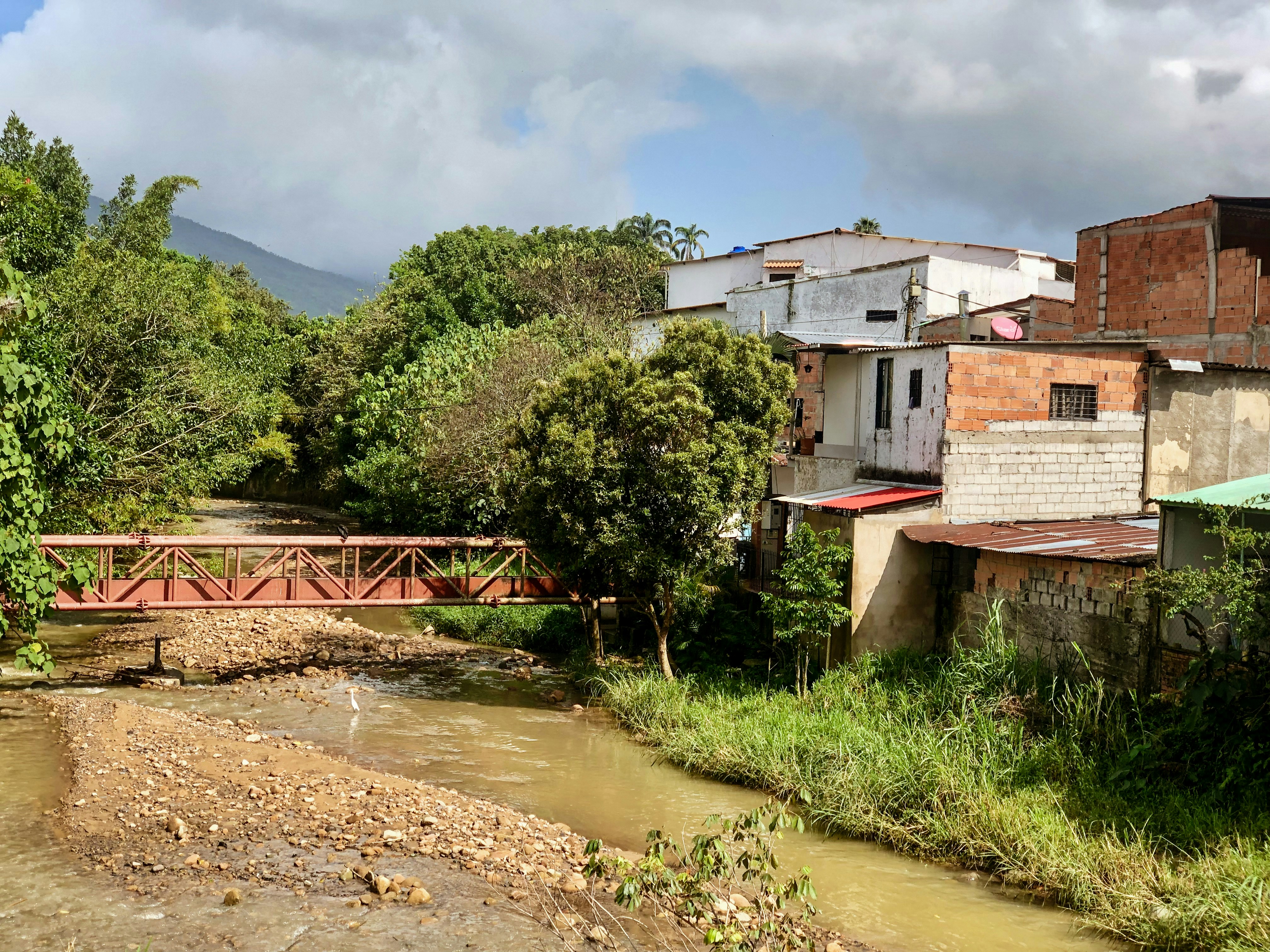 Rural bridge over stream, bright natural daylight, open landscape, community infrastructure