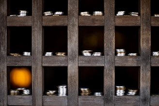 Display case filled with shiny gold and silver coins under warm lighting in a cozy store.
