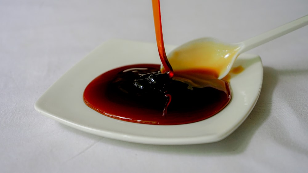 a spoon is pouring sauce on a white plate