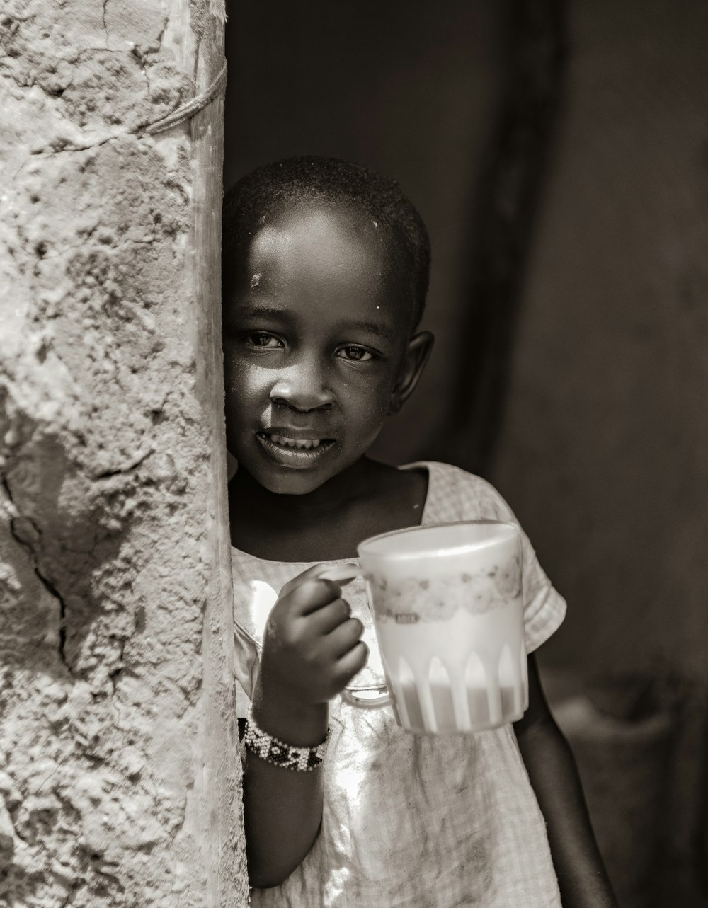 a young girl is holding a cup and smiling