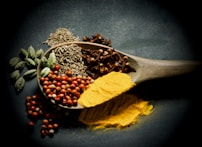 a wooden spoon filled with different types of spices