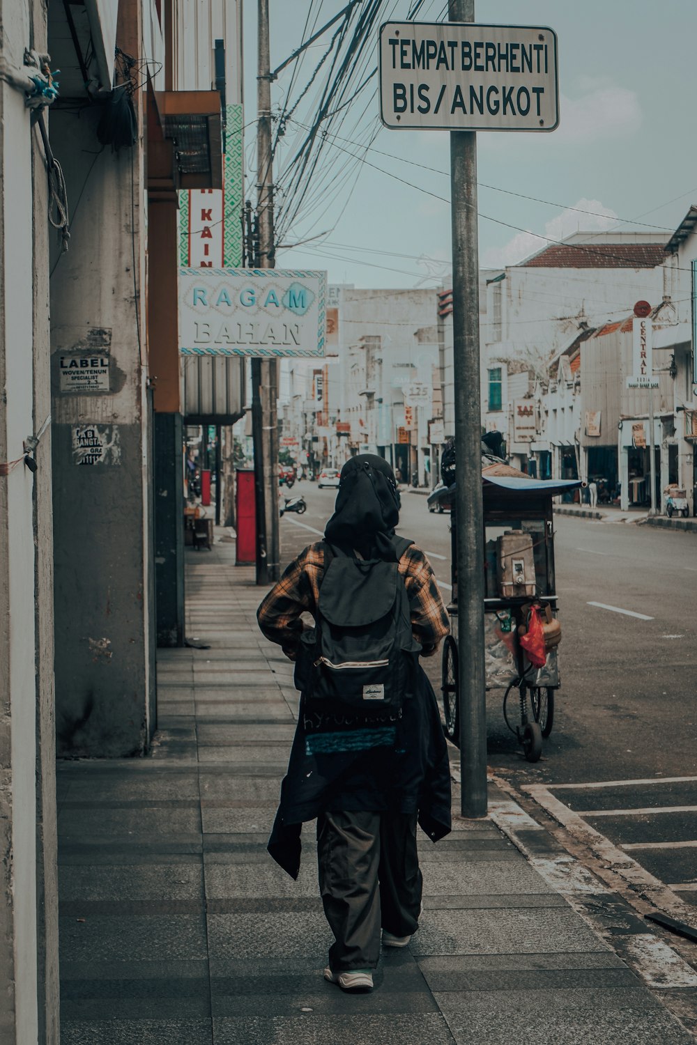 a person walking down a street next to a street sign