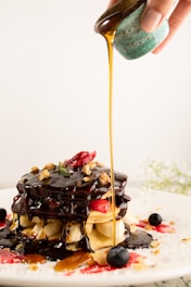 A stack of fluffy poffertjes dusted with powdered sugar and drizzled with honey.