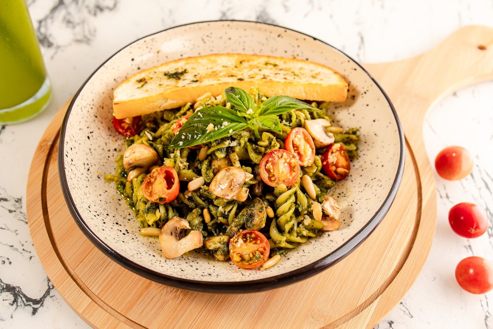 a plate of pasta with pesto and bread