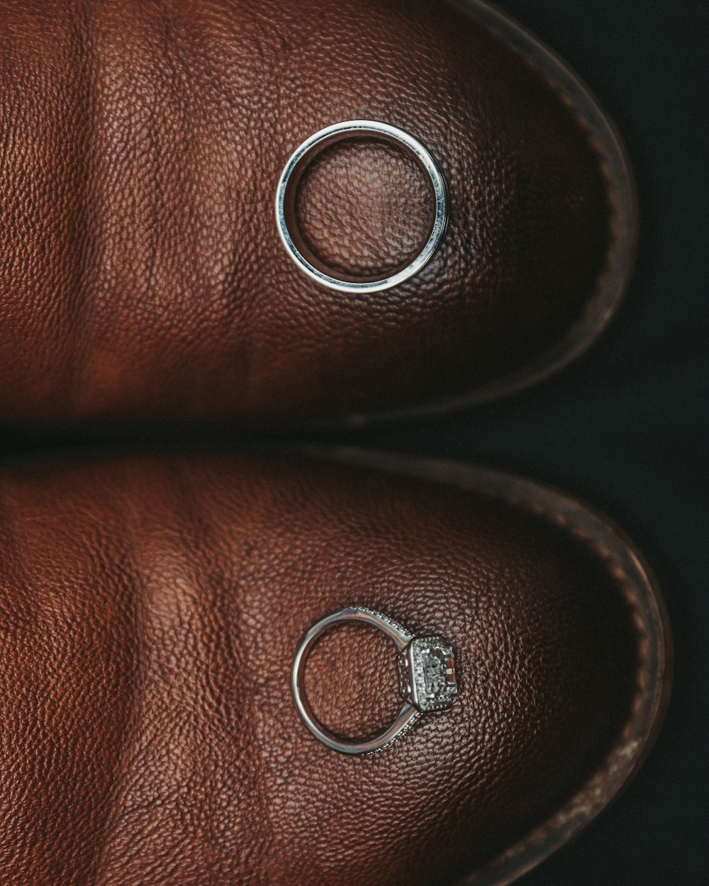 a pair of brown leather shoes with silver rings on them