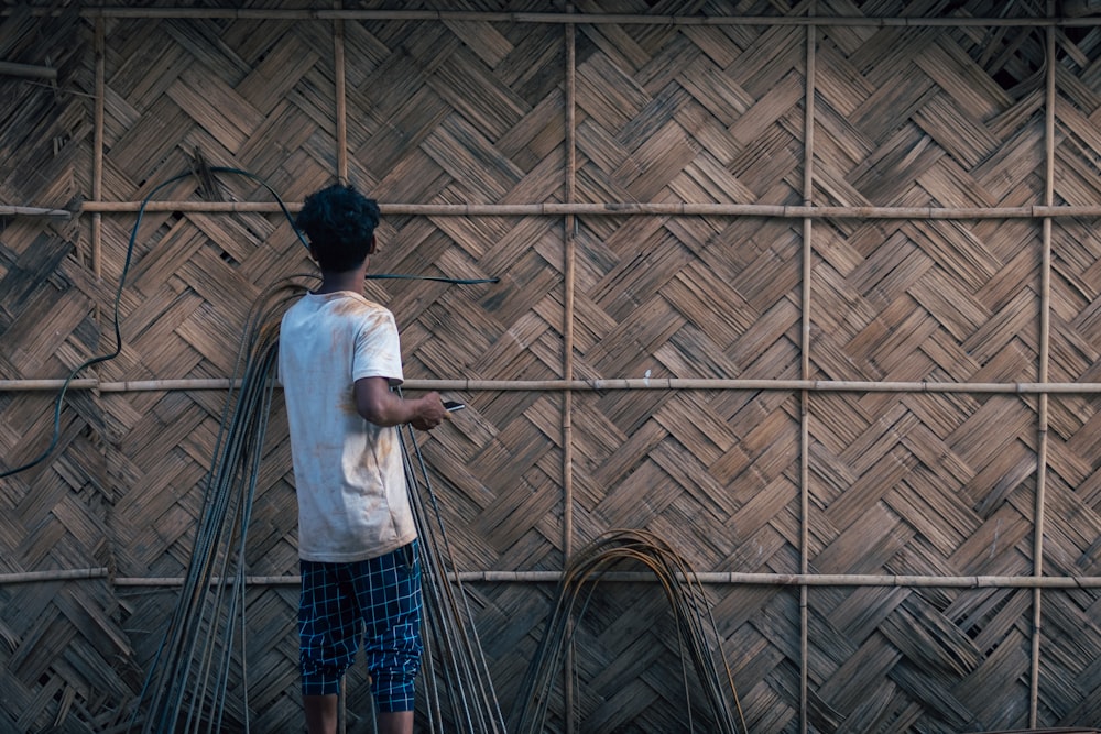 a man standing in front of a bamboo wall