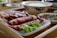 A plate of raw, marbled beef slices is attractively arranged, accompanied by fresh green lettuce. Nearby, a small dish holds a flavorful dipping sauce garnished with herbs and chili pieces, and a bowl of white rice sits in the background.