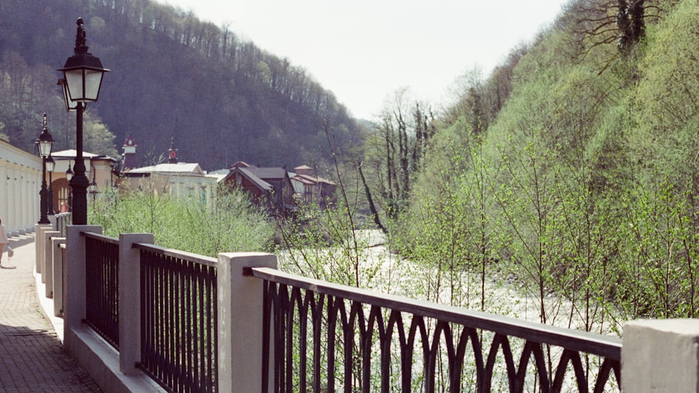 a woman walking down a sidewalk next to a forest