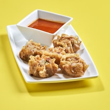 Close-up of a vibrant plate featuring golden fried dumplings with dipping sauce.