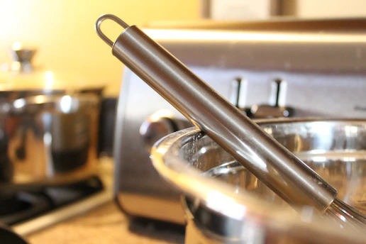 Close-up of a sleek stainless steel kitchen gadget resting on a rustic wooden countertop.
