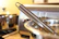 Close-up of a shiny stainless steel spatula resting on a wooden kitchen counter with fresh vegetables in the background.