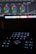 A dark setting with an illuminated control panel. The top of the image shows a computer screen displaying color wheels for video or photo editing. Below, a control surface with buttons and dials is dimly lit. The surface features a central dial with options like play, pause, fast forward, and reverse.