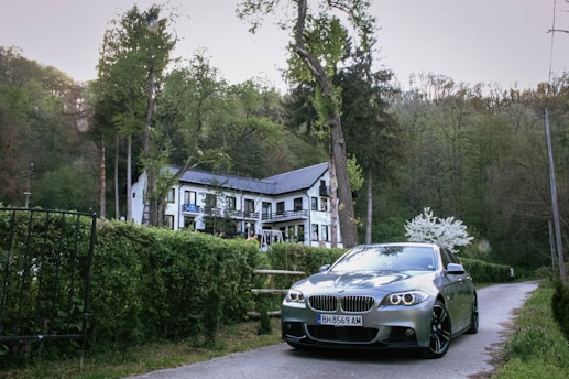 A sleek rental car parked in front of a cozy villa surrounded by greenery.