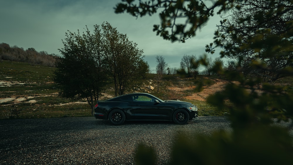 a black sports car parked on a gravel road