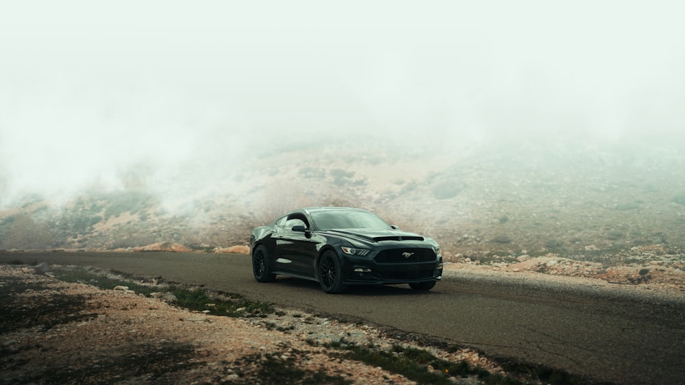 a black sports car driving down a mountain road