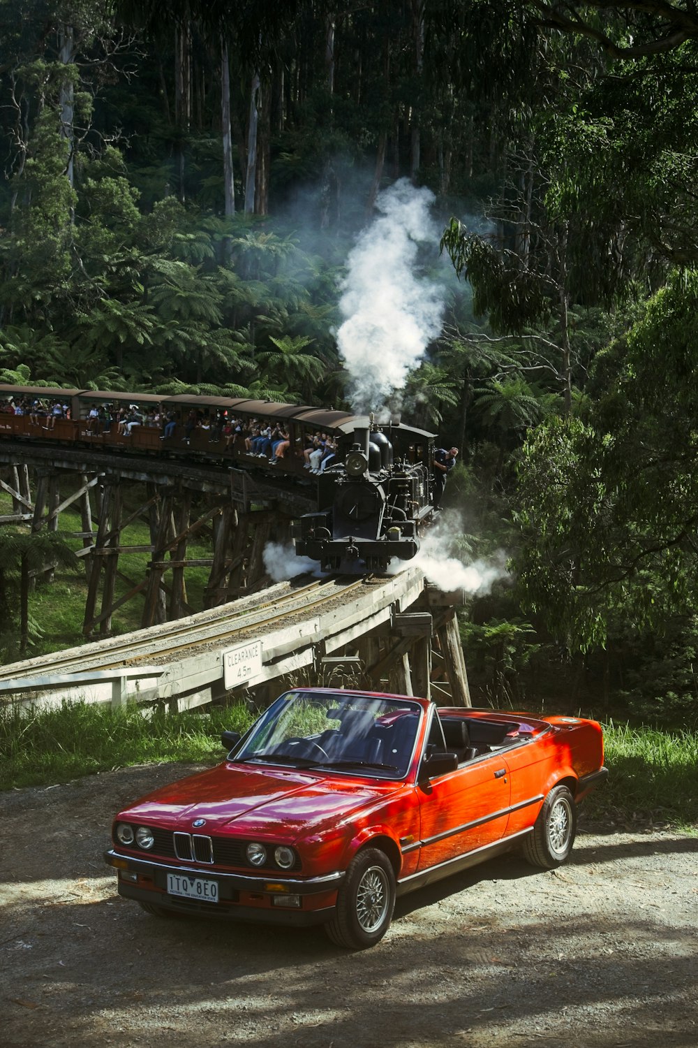 a red car parked next to a train on a track