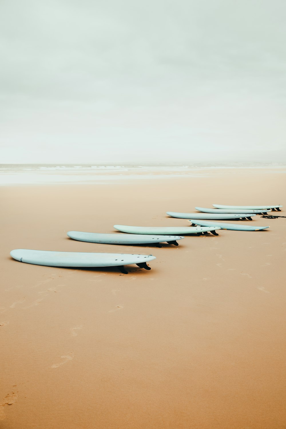 uma fileira de pranchas de surf sentadas no topo de uma praia de areia